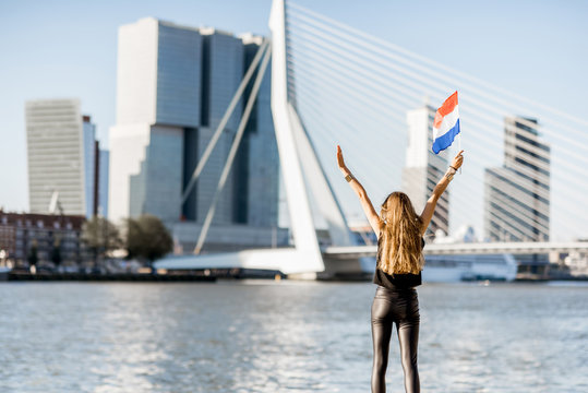 Woman with dutch flag enjoying beautiful cityscape view on the modern riverside during the morning in Rotterdam city