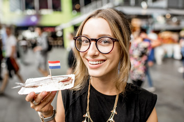 Young woman eating herring with onions traditional dutch snack in Rotterdam market