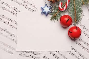 Beautiful composition with paper card and decorations on music sheets. Christmas songs concept