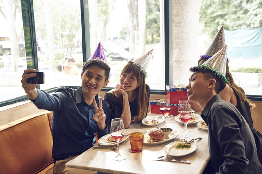 Four happy friends taking a selfie in a restaurant