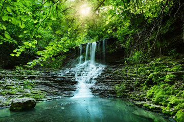 Beautiful mountain rainforest waterfall with fast flowing water and rocks, long exposure. Natural...