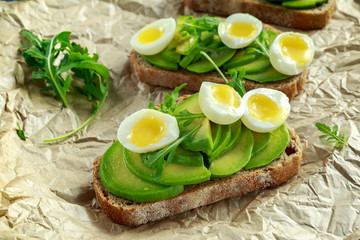 Healthy Avocado and quail eggs toasts with wild rocket and sea salt