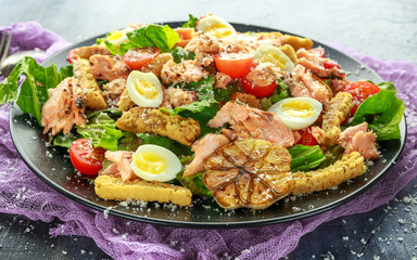Cesar salad with salmon, cherry tomatoes, garlic, crutons, romaine lettuce and parmesan.