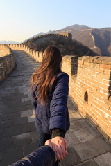 Beautiful girl holding a man's hand. Couple at the the Great Wall of China.