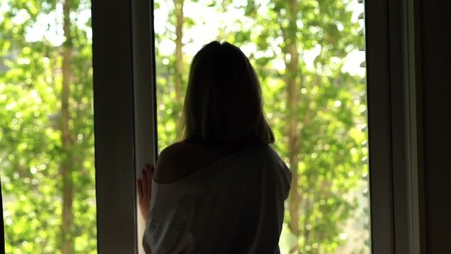 Woman unveil curtains stretching and walking out on terrace
