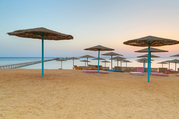 Fototapeta premium Sunrise under parasols on the beach of Red Sea, Egypt