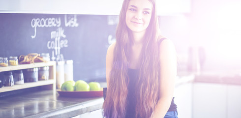 Beautiful woman cooking cake in kitchen standing near desk