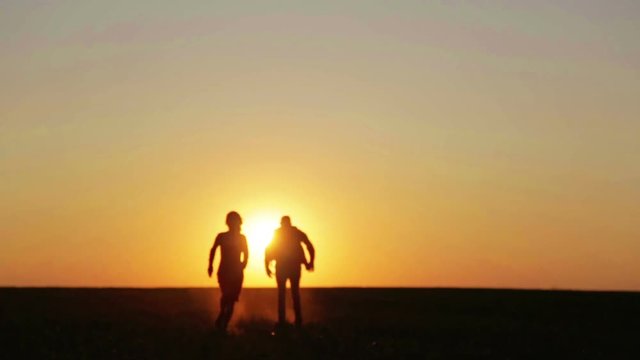 Man and woman in the field at sunset. A couple at sunset runs and jumps into the field.
