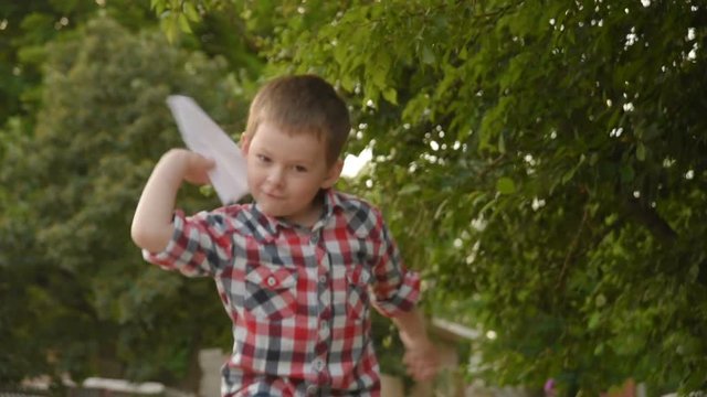 little boy launches a paper plane. slow motion