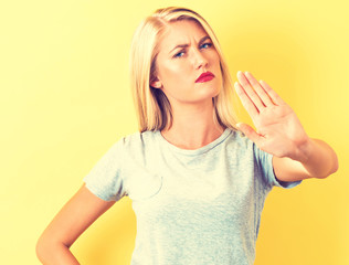 Young woman making a rejection pose on a yellow background