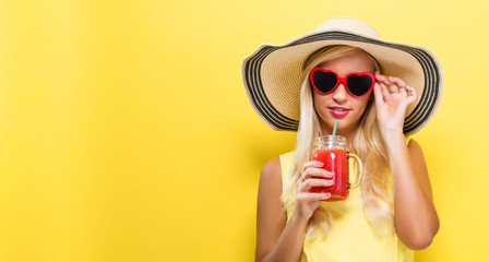 Obraz premium Happy young woman drinking smoothie on a yellow background