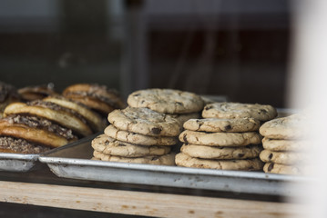 A tray of chocolate chip cookies is seen in the window of a bakery.