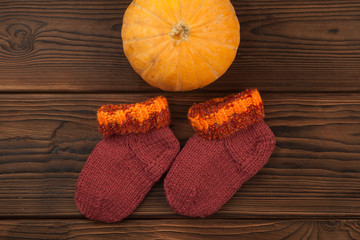 Pumpkin and woolen socks on old rustic wooden table. Halloween background with pumpkin