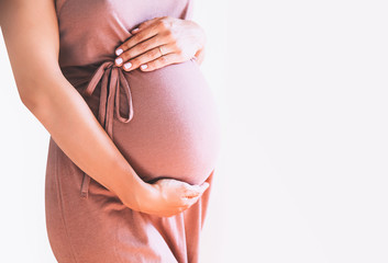 Pregnant woman holds hands on belly. Close-up