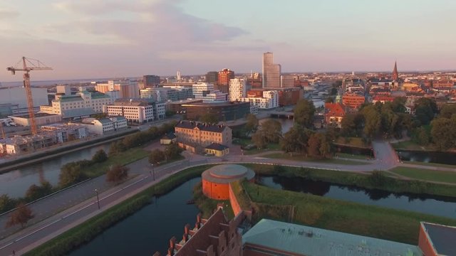 Aerial view flying over Malmo Castle and cityscape at sunset. Drone shot of "Malmohus" in Sweden, construction site and city in the background