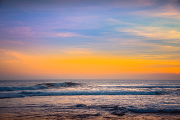 Naklejka na ściany i meble Colorful Background Sunset. Blue Waves near sea Resort. Sunset Background Ocean. Tropical Sunlight and Summer Sunset View. Isolated Sea Sunset. Surfing Beach with Surfers on the Horizon. Landscape