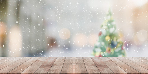 Wood table top on blur with bokeh christmas tree background with snowfall - can be used for display...