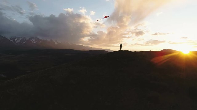 woman silhouette mountain golden sunset sky flying long tailed toy kite. 4k slow motion