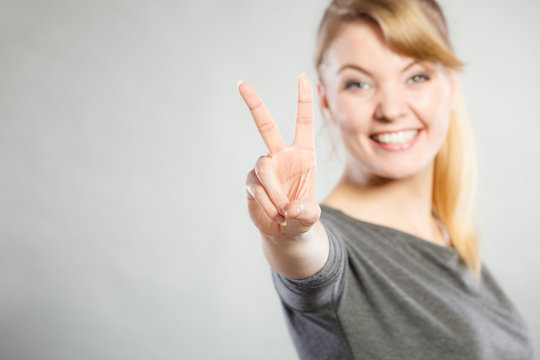 Cheerful lady makes v gesture.