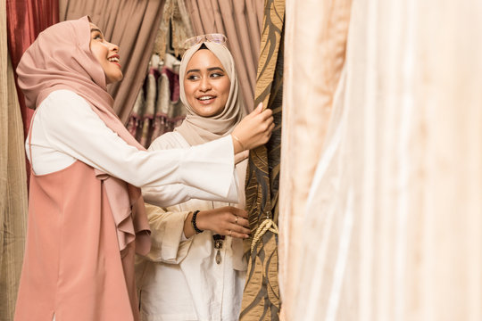 Two women in headscarves shopping for curtains