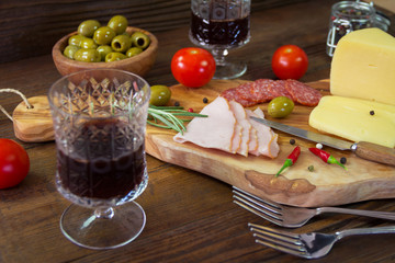 Appetizer on a wooden board with wine and olives for two