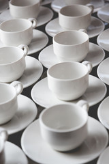 Large group of white coffee tea cups arranged in rows