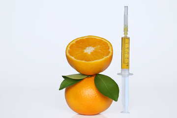 serum with  vitamin C in a syringe and  orange  with leaves on a white background.