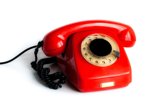 An old red phone against a white background