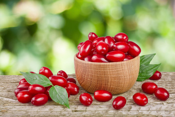 dogwood berry with leaf in bowl on wooden table with a blurry garden background