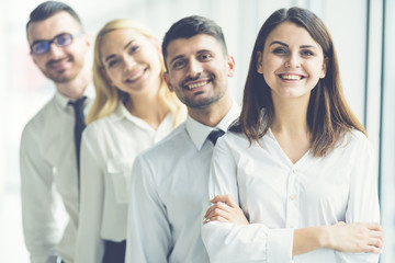 The happy business people stand near the office window
