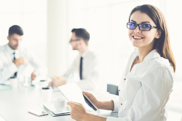 The businesswoman with a tablet sit near colleagues