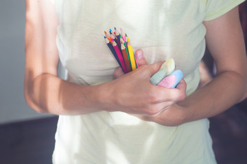 holding many colorful wooden pencils Crayons in closeup