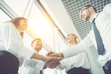 Fototapeta premium The four business people hold hands together on the sunshine background