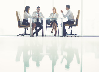 The four business people sit at the table on the conference