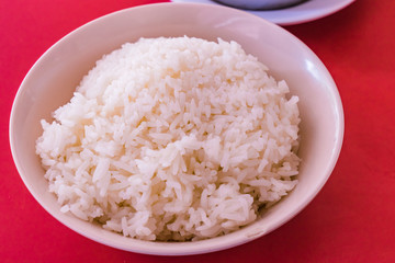 Cooked Jasmine Rice in white bowl and red table background