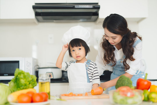 Happy family in the kitchen. Mother and child daughter are preparing the vegetables and fruit.