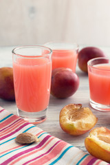 Plum juice. Pink drink on a white wooden table with striped napkin.