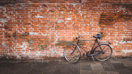 Old bike in a brick wall with the tire flat