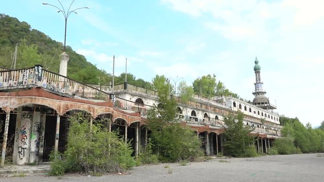 Abandoned building with murals and minaret in Consonno, Italy. Rusted construction with graffiti and wild vegetation, desolate and scary place, ghost town