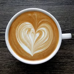 Zelfklevend Fotobehang Top view of a mug of latte art coffee on timber background. © tanarch