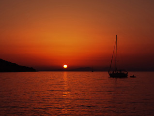 Sailboat sailing from Syvota's ( Greece) port toward sunset on calm evening
