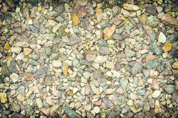 Photo rash of small colored stones close-up with black ventilation around the edges under the background or inscription