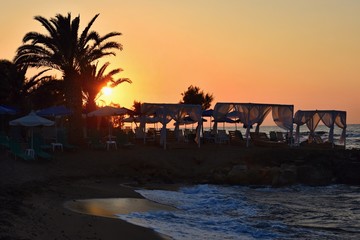 Beautiful summer sunset by the sea. Amazing scenery on the beach with waves and reflection of the sun. Background for holiday and vacation travel. Greece Crete Island.