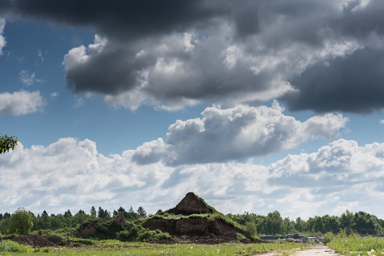 The old pyramid near the green forest under the white and dark clouds