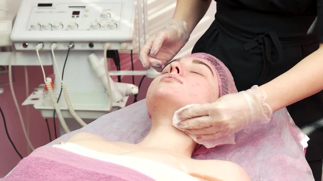 Hands of cosmetician cleaning face. Girl with problematic skin. Astringents for acne.