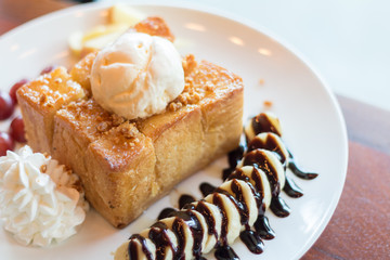 Honey toast with vanilla ice cream, whipped cream and chocolate syrup. Served with banana, grape and apple(selective focus)
