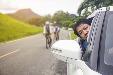 Men look out of the car window. To see people cycling in the back.