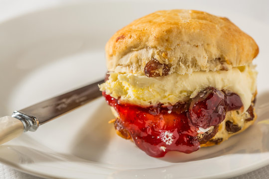 Scone with clotted cream ans strawberry jam on white plate