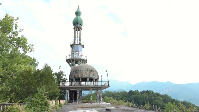 Abandoned minaret Arabian style, destroyed building with murals in Consonno, Italy. Arabic style construction with graffiti and wild vegetation, godforsaken and scary place, ghost town