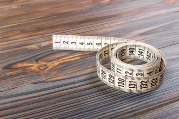 Close up tailor measuring tape on wooden table background. White measuring tape shallow dept of field.